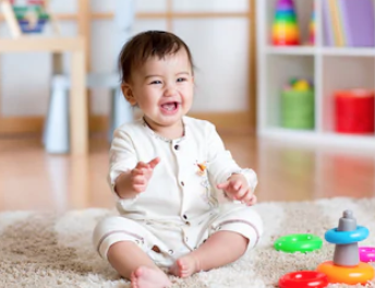 Infant sitting on a cream rug and smiling